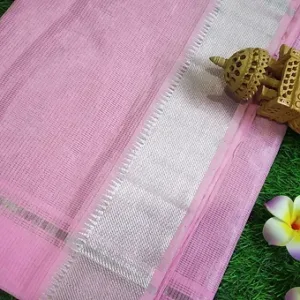 Close view of a light pink Mangalgiri handloom pure cotton saree featuring a simple textured weave and a broad silver zari border, displayed on a green grass background with decorative elements.