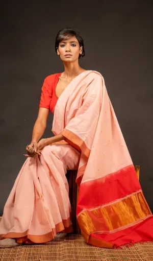 Peach handloom pure cotton Mangalagiri saree with red and gold Nizam border, worn by woman in traditional style