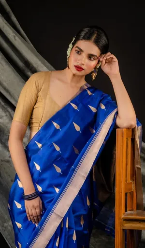A woman wearing a blue Chanderi saree with gold leaf patterns, paired with a beige blouse and traditional jewelry.